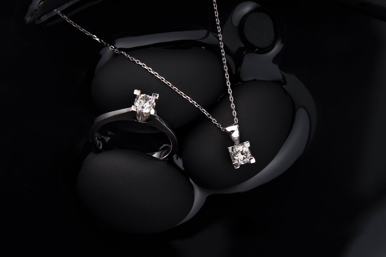 Luxurious silver diamond ring and pendant necklace on a black background, showcasing elegance and sophistication.